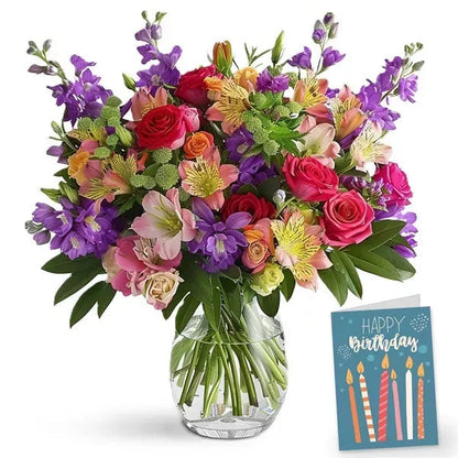 Colorful bouquet of mixed flowers in a glass vase with a 'Happy Birthday' card.