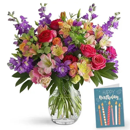 Colorful bouquet of mixed flowers in a glass vase with a 'Happy Birthday' card.