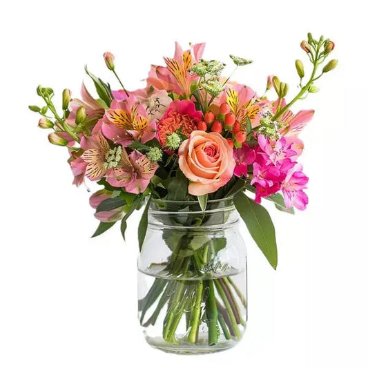 A bouquet of pink flowers and a peach rose in a glass jar on a white background.