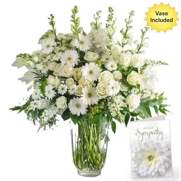 A large bouquet of white flowers in a vase with a sympathy card.
